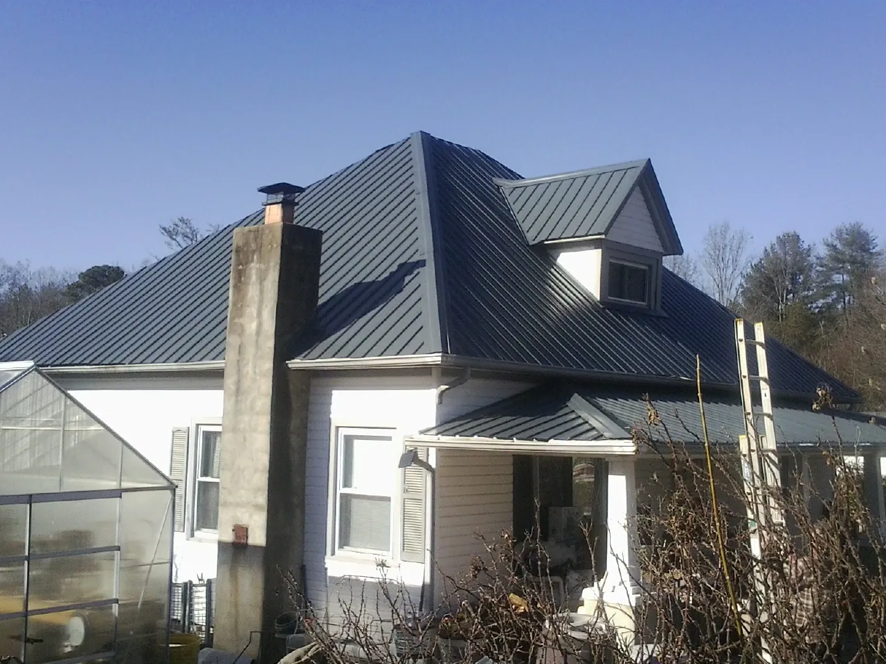 Dark blue standing seam metal roof on a white farmhouse with dormer — Slate & Tile Roof Repair by Roofing Brothers in Mineville