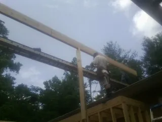 Carpenter setting a ridge beam over a new addition frame — Ice Dam Removal by Roofing Brothers in Mineville