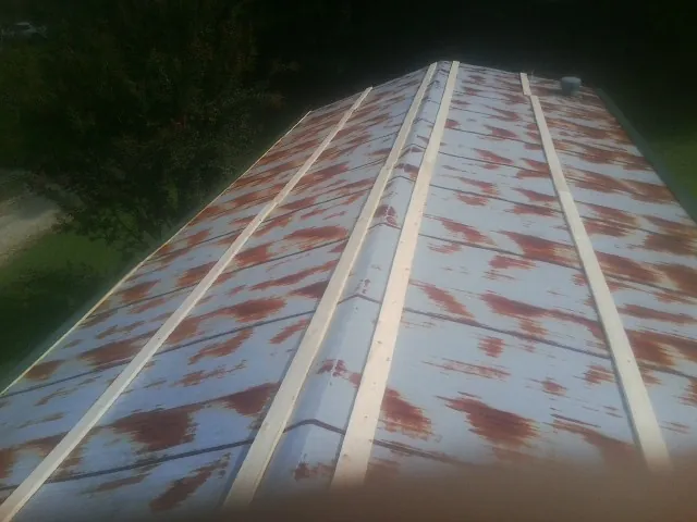 Rusted metal roof panels with new wood purlins before replacement in Mineville