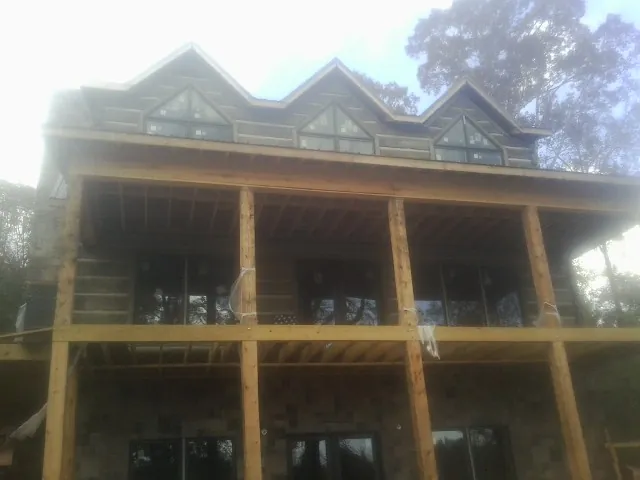 Dormers and porch framing on a large log home under construction — Roof Coating work by our crew in Mineville