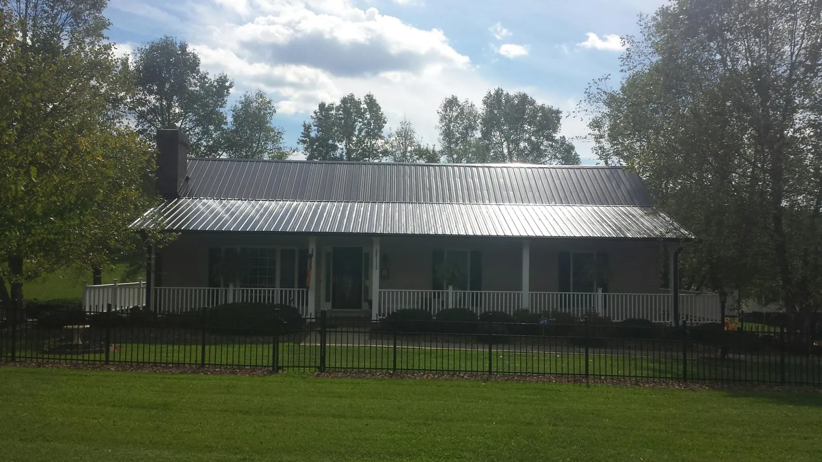 Gray metal roof on a brick ranch with a full width front porch — Gutter Guard Installation work by our crew in Mineville