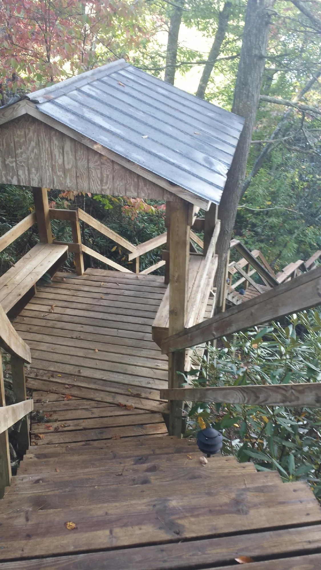 Metal roofed shelter over wooden steps on a wooded walkway — Skylight Repair & Installation work by our crew in Mineville