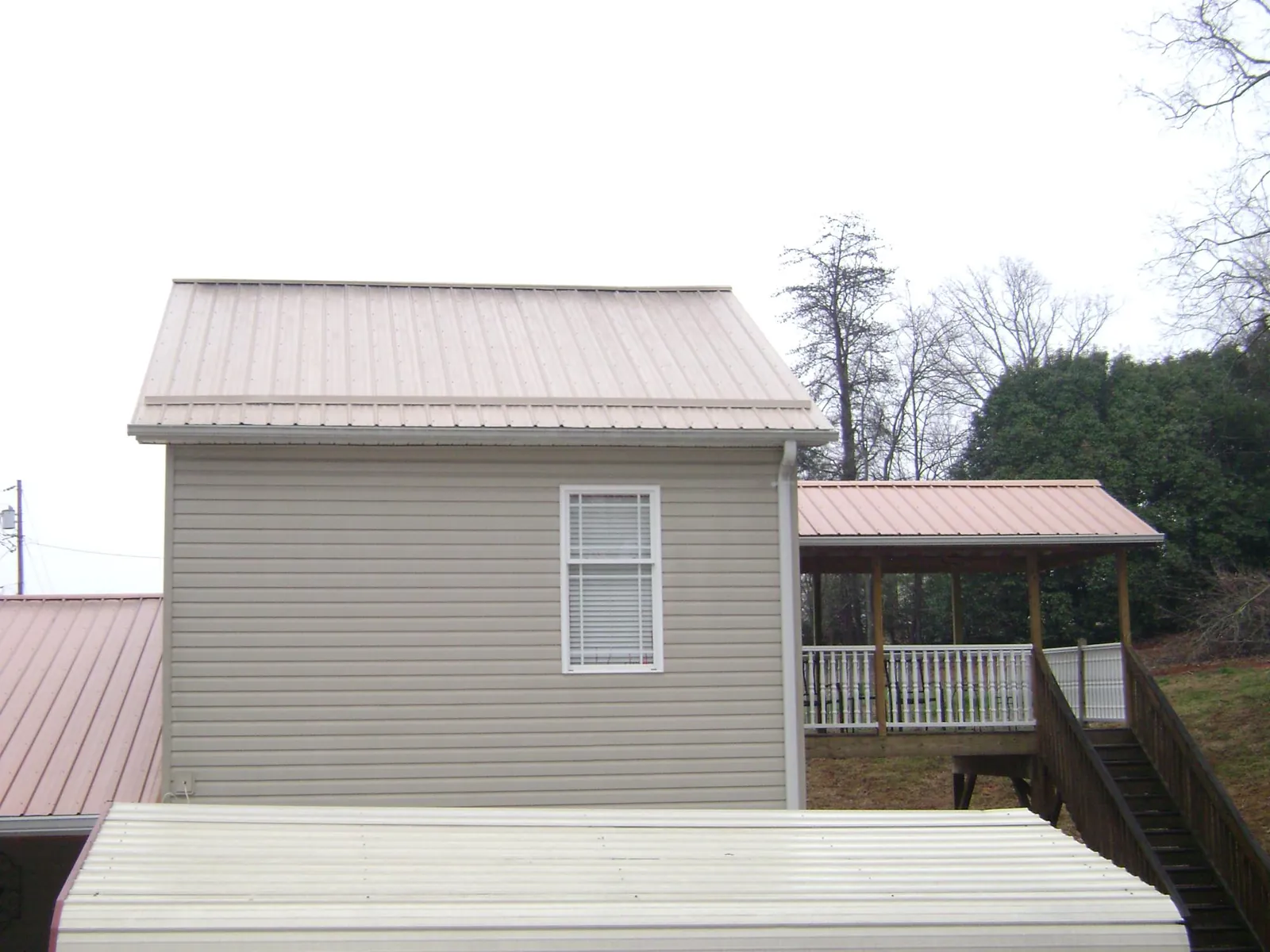 Tan metal roofs on a two story addition and attached porch, from a Roof Replacement job in Mineville