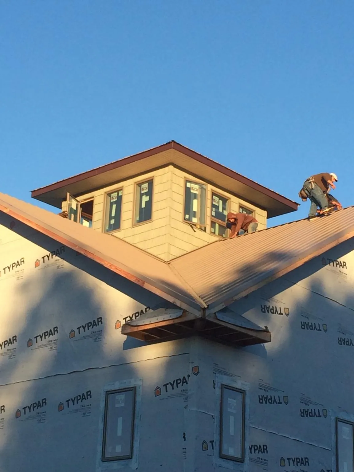 Roofers working around a rooftop cupola on a new metal roof at sunset — Roof Waterproofing in Mineville by Roofing Brothers